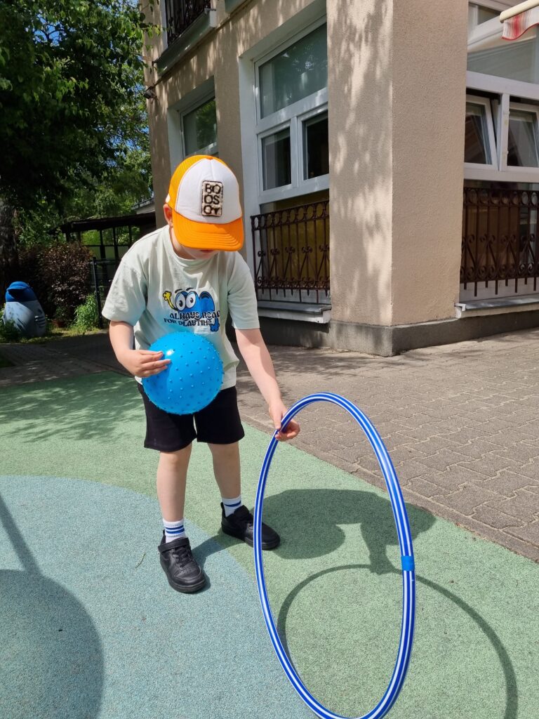 Chlopiec bawi się hula hop w ogrodzie przedszkolnym.