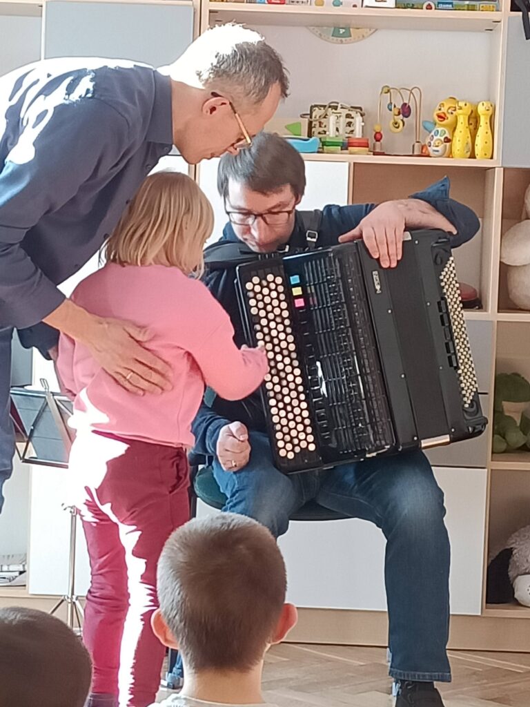 Dziewczynka naciska klawisze na akordeonie.